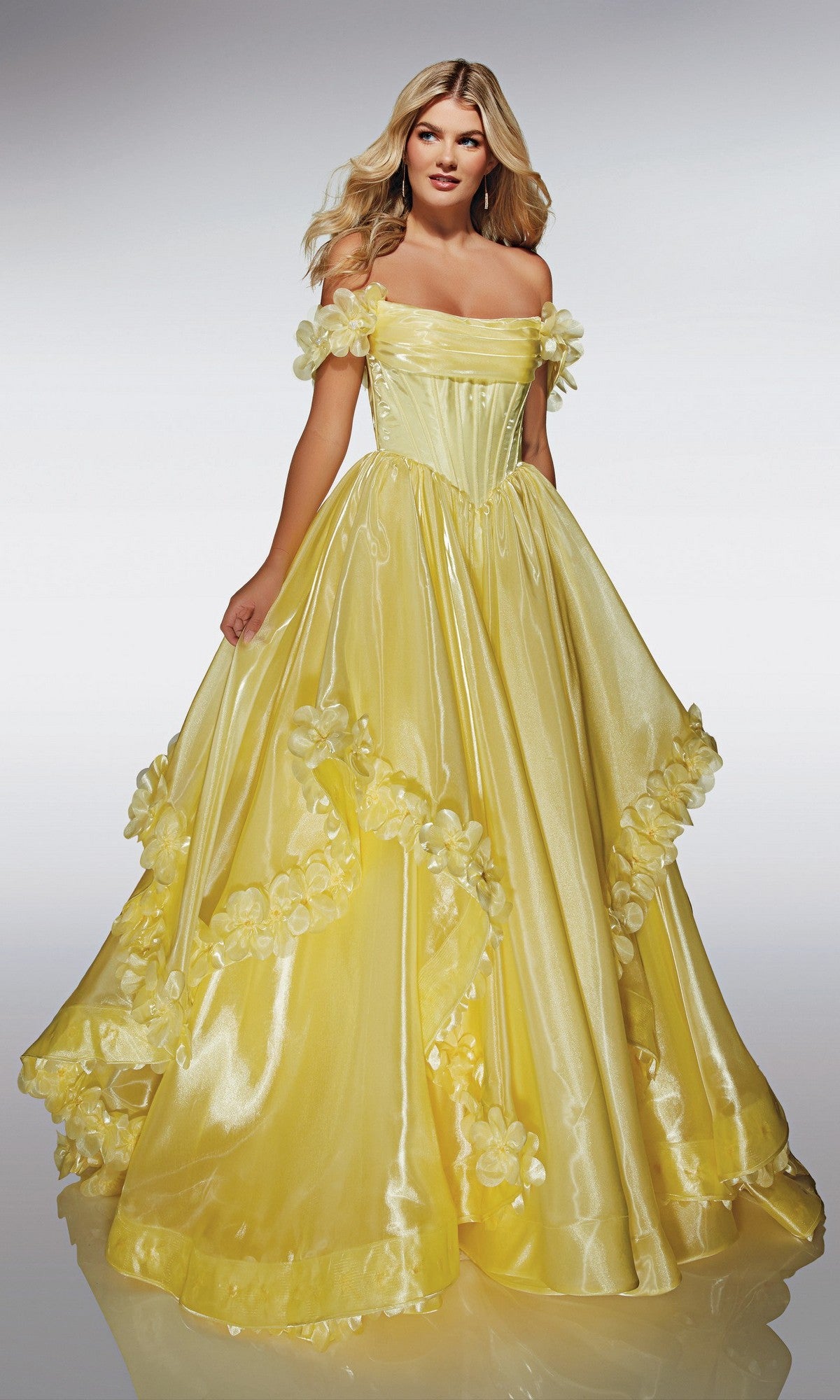 A woman models the Alyce 62014 long prom dress, a shiny yellow strapless ballgown with 3D floral appliques, set against a plain light background.